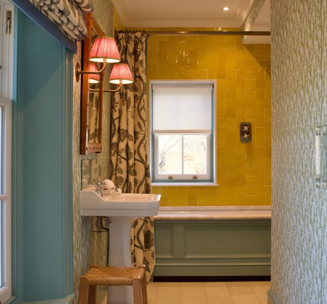 . A children’s bathroom full of colour . There is a shower above the bath with the shower rose recessed into the ceiling to gain maximum height . The shower curtain has a waterproof lining that falls into the bath to stop water from escaping and the window architrave is made of matching stone to the bath top surround . So practical and looks good! .
